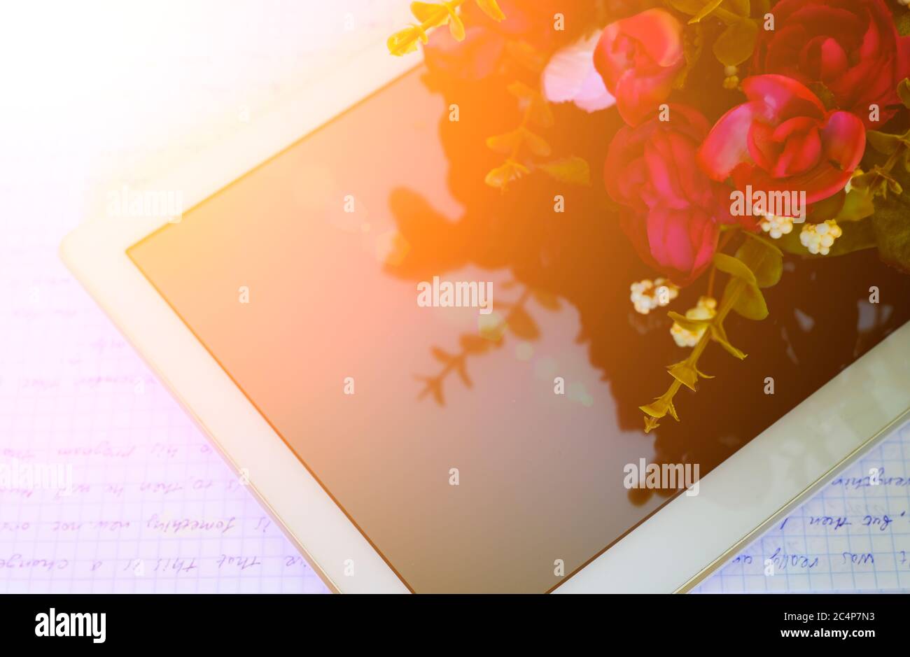 Ein PC-Tablet mit einem Blumenstrauß auf dem Tisch. Alles gute zum Tag des Lehrers. Schulungsraum. Draufsicht. Beginn des Schuljahres. Zurück zur Schule Konzept Stockfoto