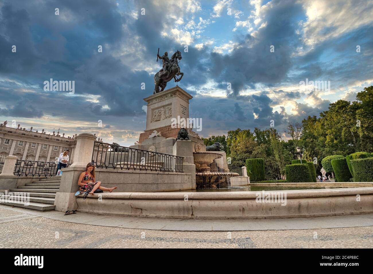 MADRID, SPANIEN - 2018. AUGUST 22. Reiterstatue des Königs Philipp IV. Auf einem Brunnen. Frau liest ein Buch Stockfoto