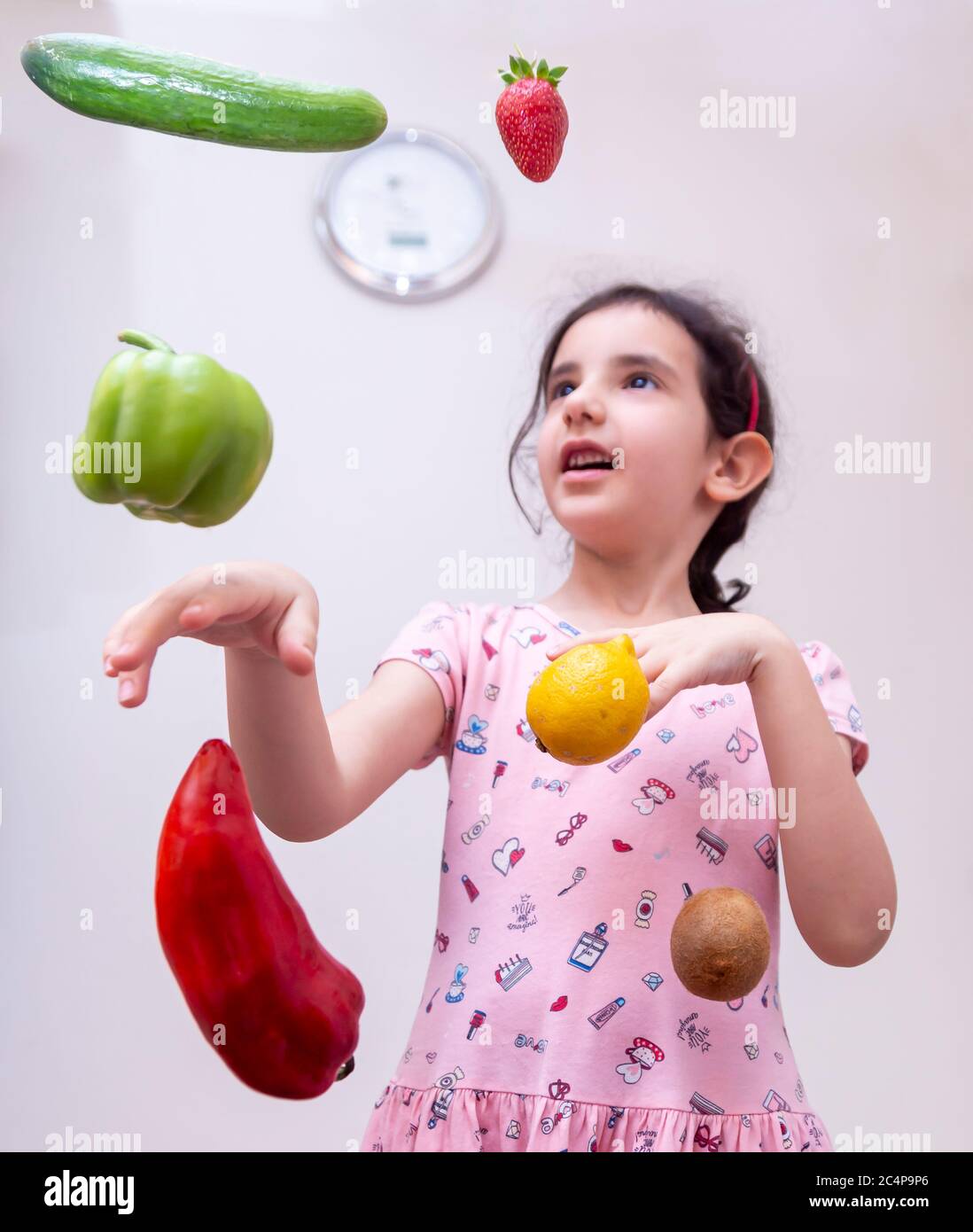 Ein kleines Mädchen spielt mit umgebenem Gemüse bei sich zu Hause Stockfoto