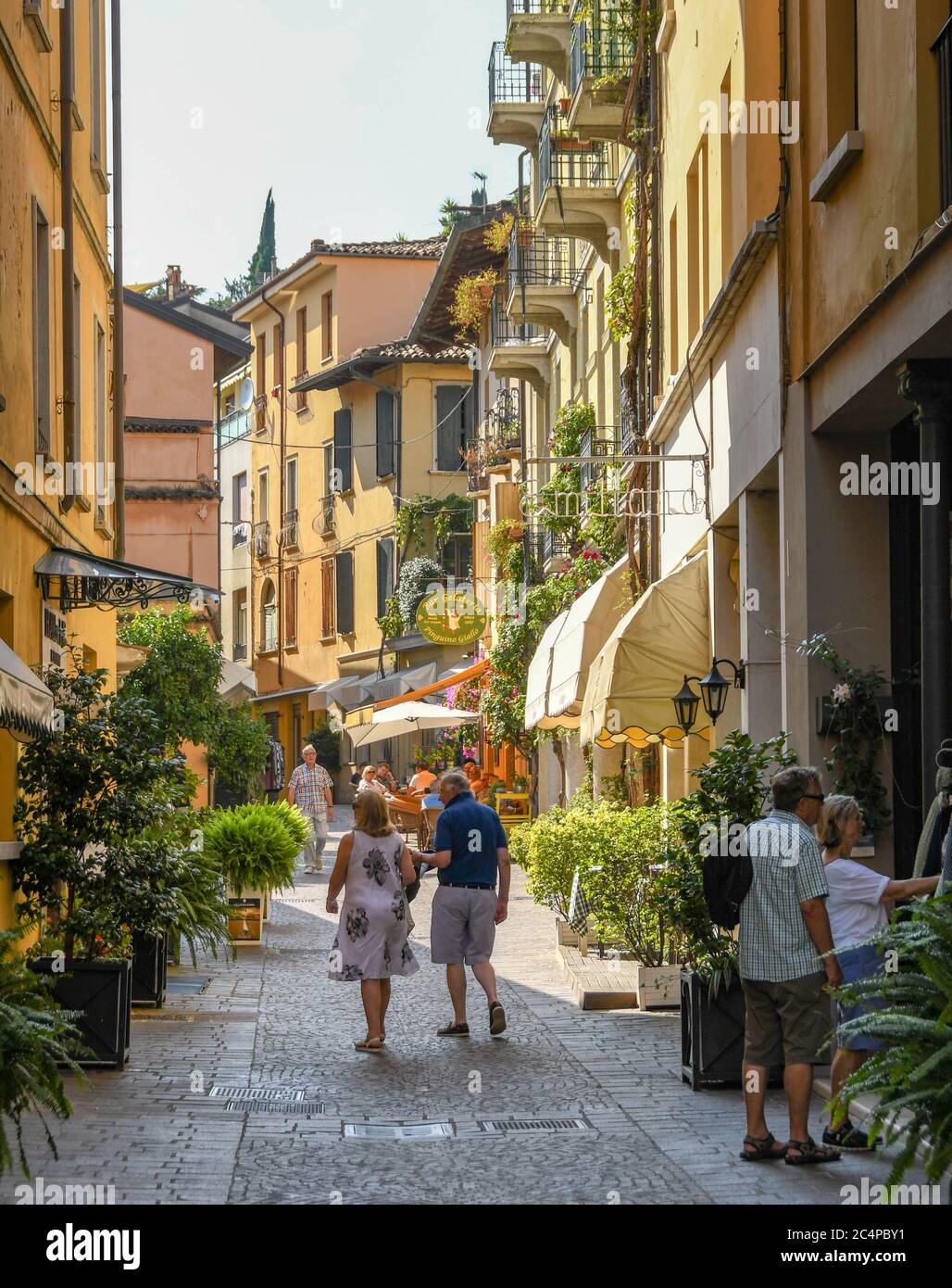 GARDONE RIVIERA, ITALIEN - SEPTEMBER 2018: Menschen, die eine schmale Straße entlang in Gardone Riviera am Gardasee gehen. Stockfoto