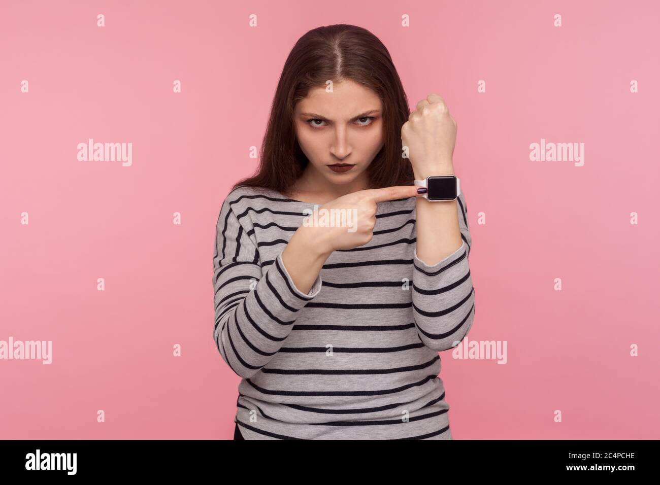 Beeil dich! Portrait der wütenden Frau im gestreiften Sweatshirt nervös über spät Stunde, zeigt Armbanduhr mit Display Mock up, ängstlich, besorgt Stockfoto