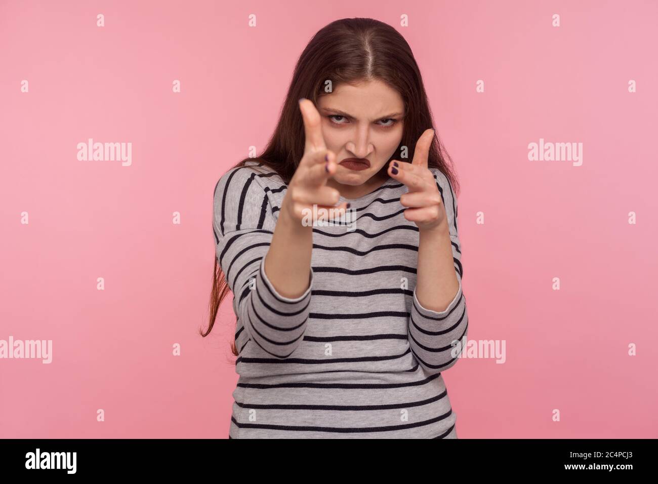 Ich werde Euch töten! Portrait von wütenden Frau in gestreiften Sweatshirt zeigt Fingerwaffen zur Kamera und sieht aggressiv, drohen zu schießen, Hände imitiert Stockfoto