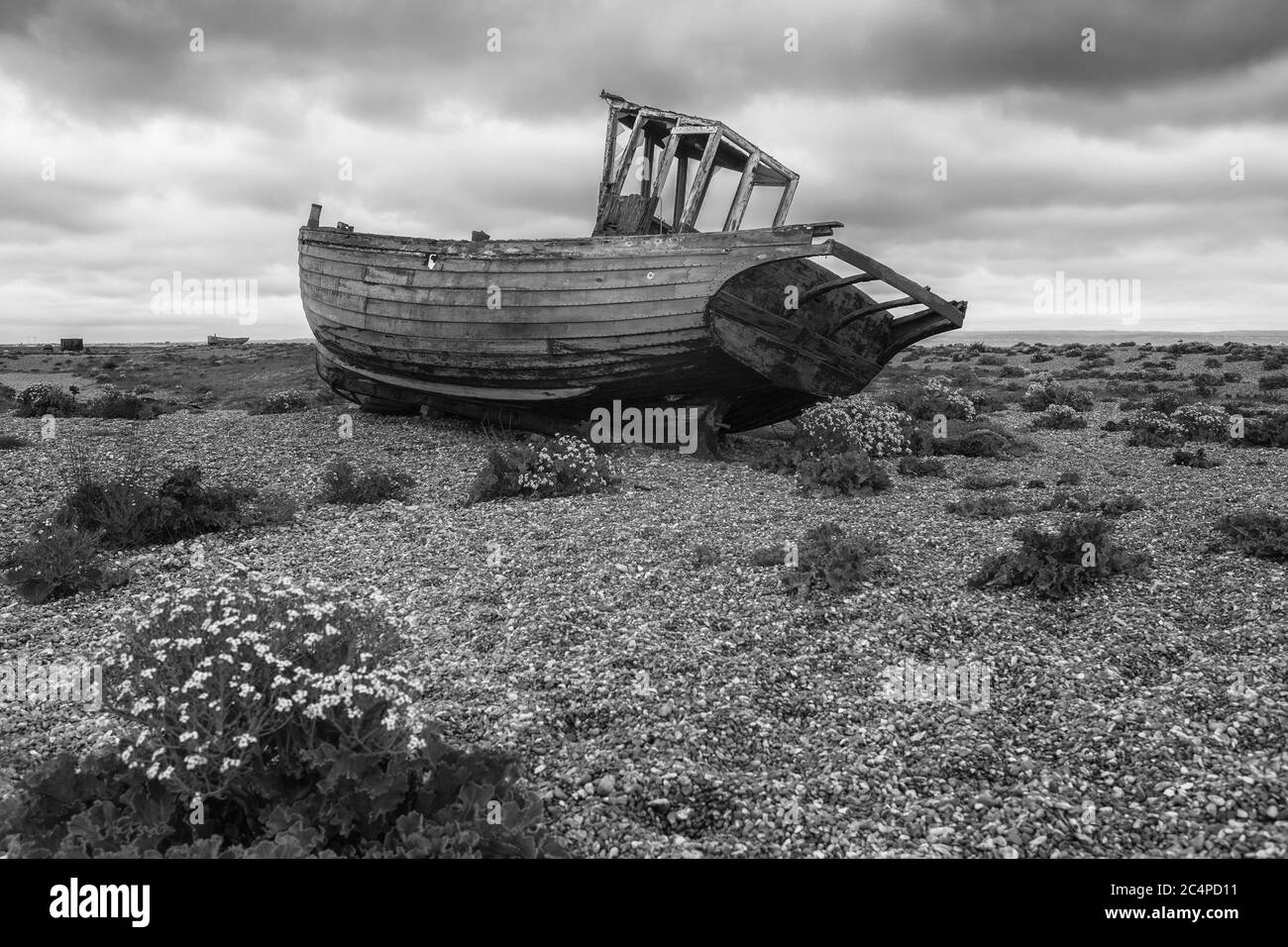 Fischerboot auf dem Schindelstrand in Dungeness, Kent, England, Großbritannien, aufgegeben. Schwarzweiß-Version Stockfoto