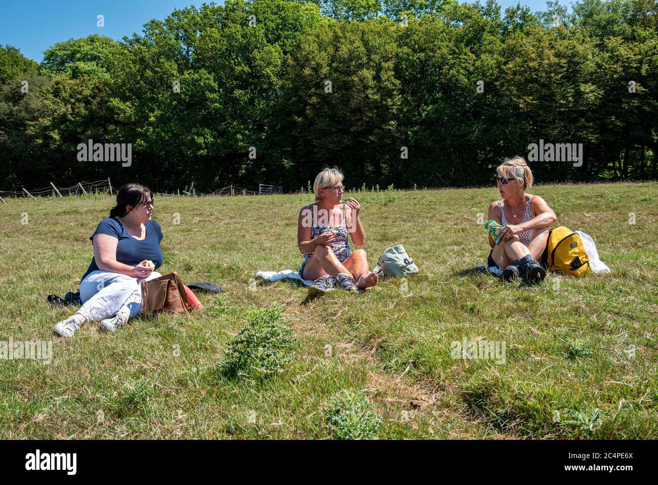 Frauen mittleren Alters sitzen bei einem Picknick in der Landschaft von Kent, während sie spazieren gehen. Stockfoto