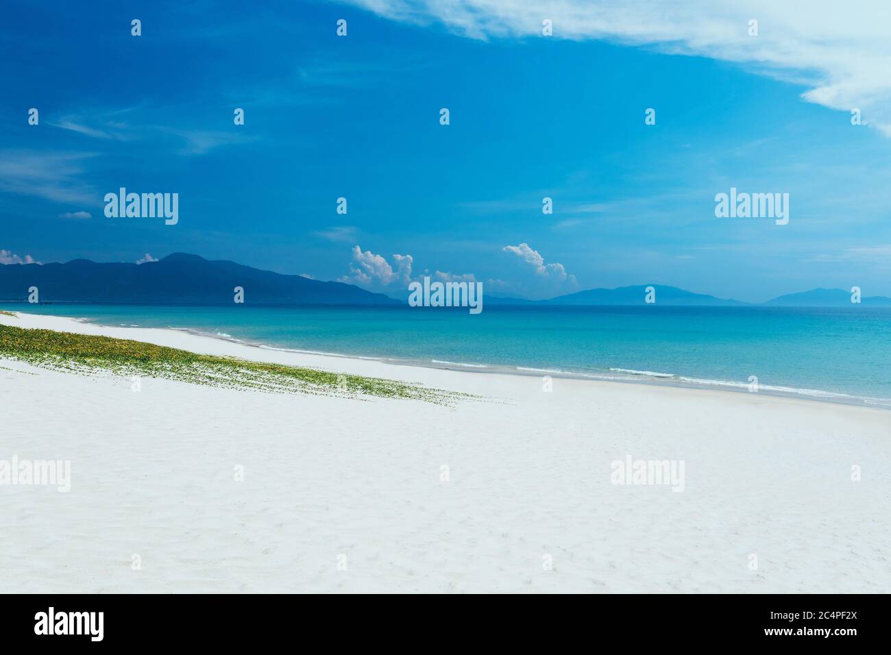 Landschaftsansicht auf den Sandstrand. Blauer Himmel mit weißen Wolken. Ein leerer langer Strand mit Meer und Berghintergrund. Sommerurlaub, Reise. c Stockfoto