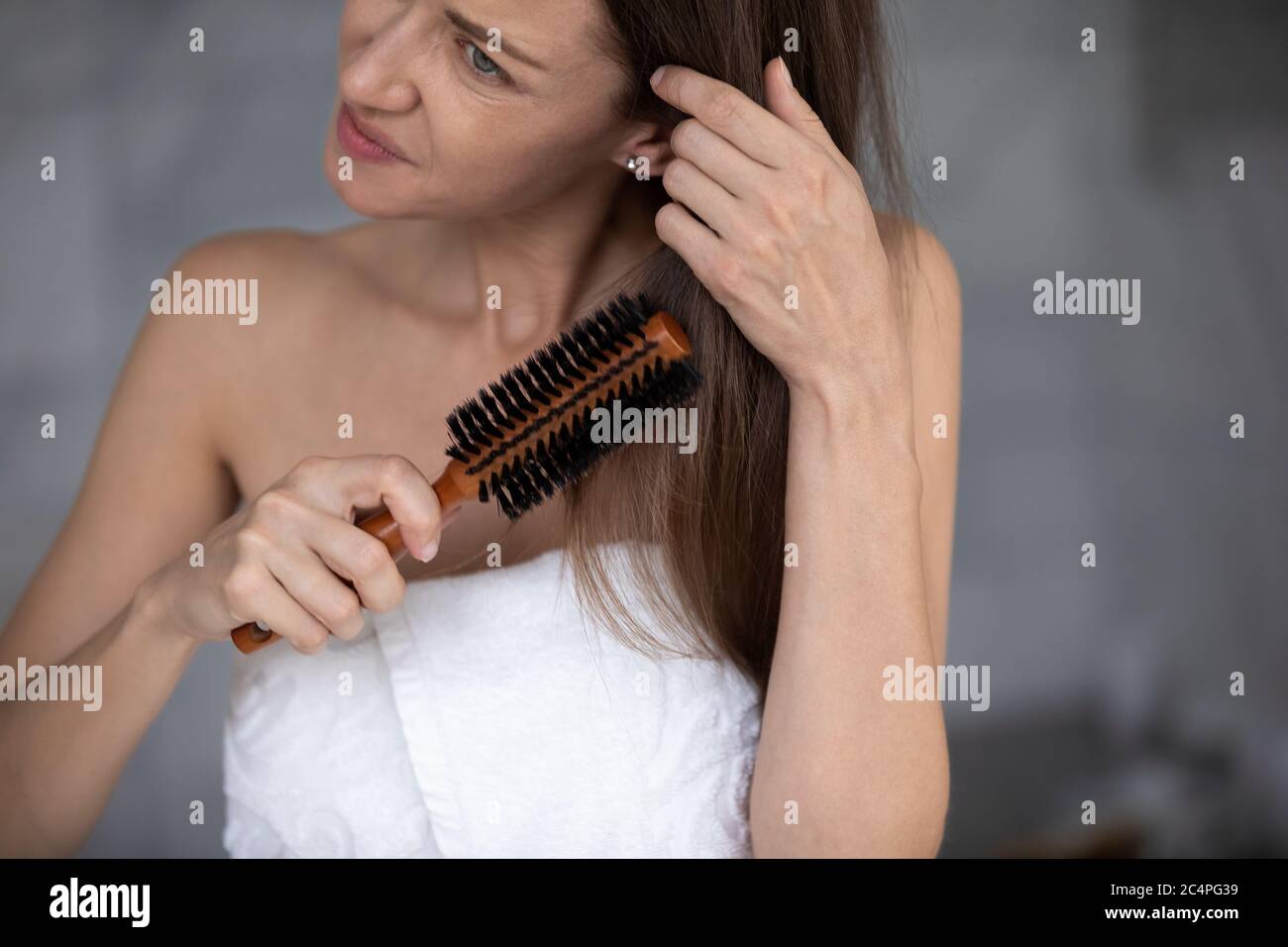 Unglückliche Frau, die morgens verworrene Haare putzt Stockfoto