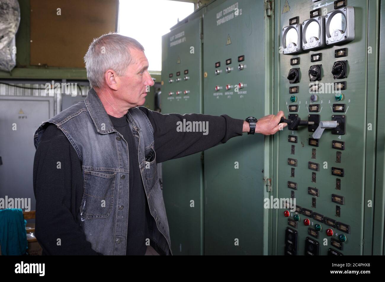 Im Kontrollraum. Arbeiter, die Tumbler an einer Hauptsteuerplatine einer Wasserversorgung drehen. Schwimmende Pumpstation Stockfoto