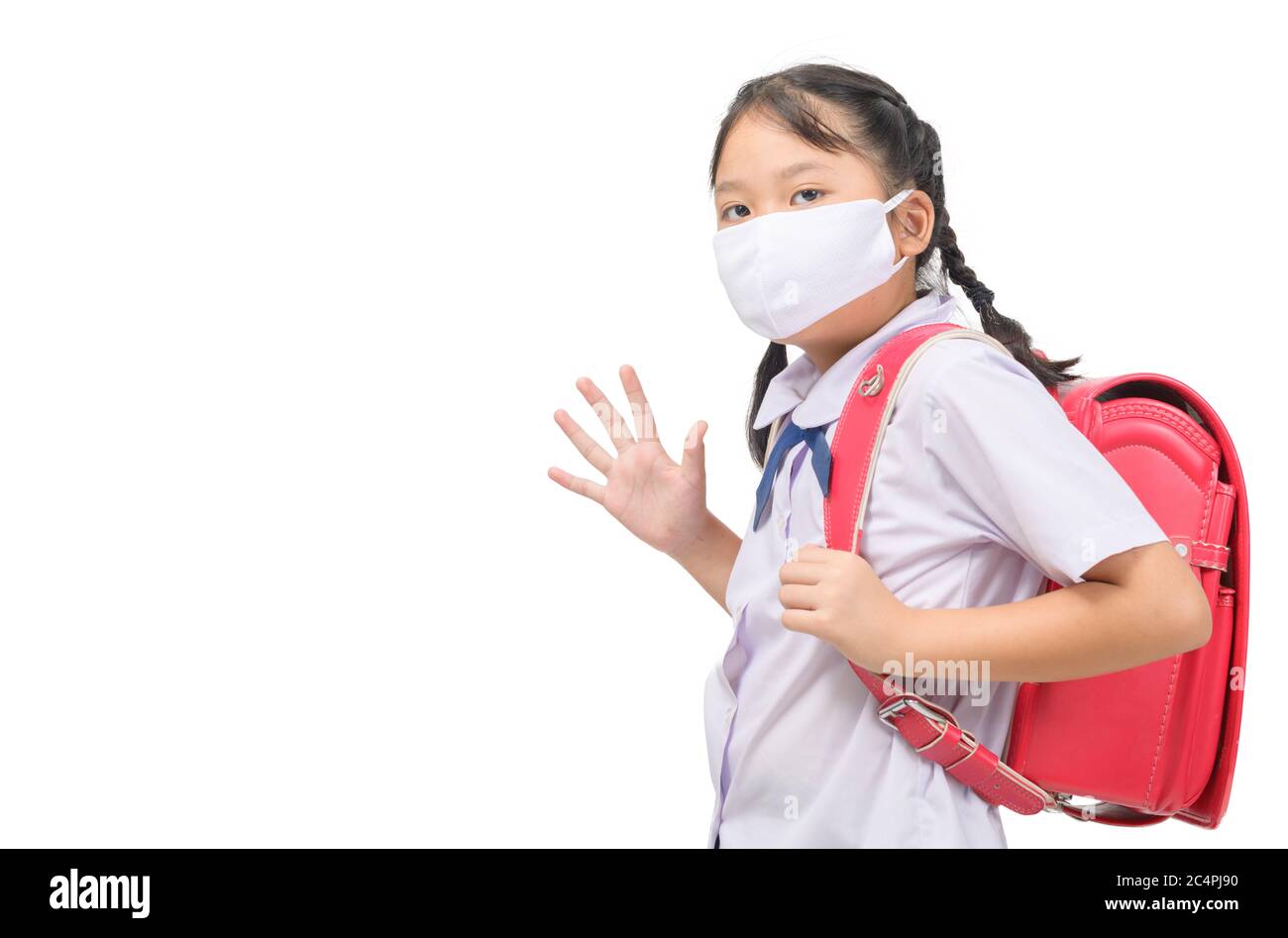 Asiatische Mädchen Schüler tragen Maske und winken Abschied vor der Schule isoliert auf weißem Hintergrund. Zurück zur Schule mit neuen normalen Konzept Stockfoto