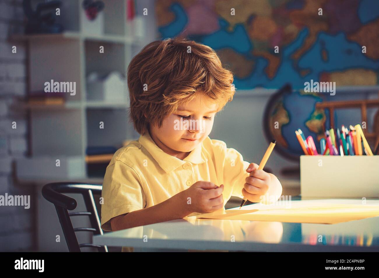Kleiner Junge Zeichnung, Bildung und Kindertagesstätte. Portrait von niedlichen Jungen mit Skizzenstift und Papier am Schreibtisch im Klassenzimmer Stockfoto