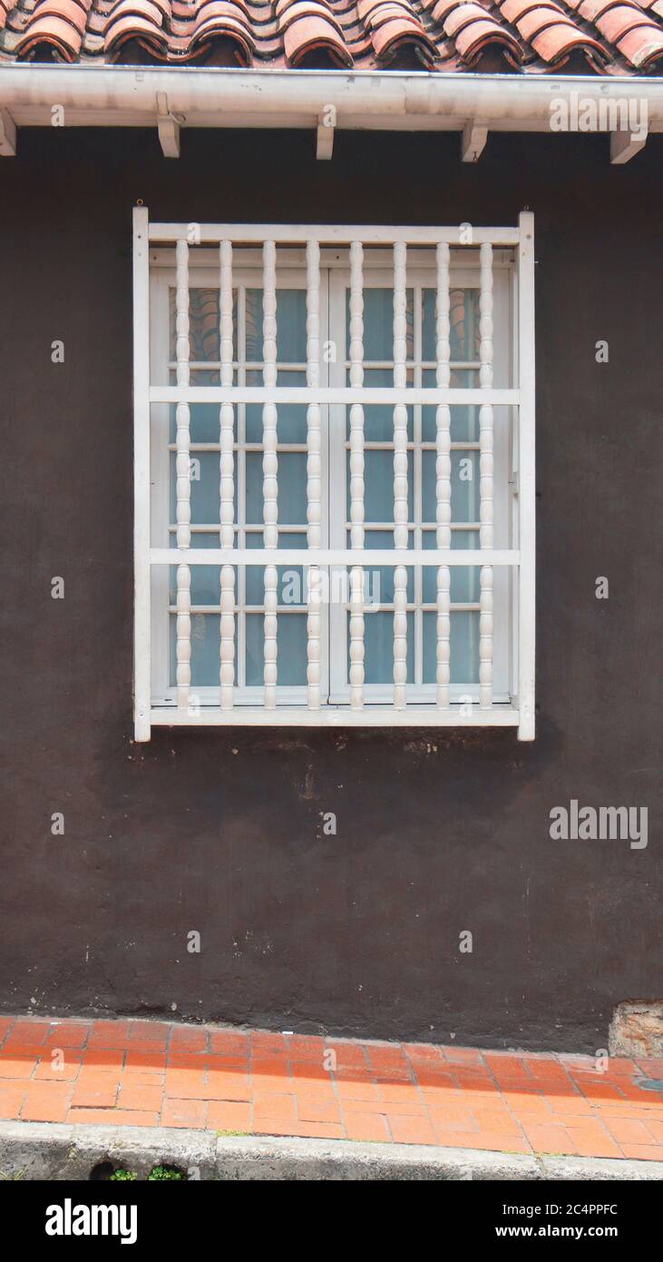 Weißes Holzfenster auf einem braunen Hintergrund mit rotem Ziegeldach im vertikalen Format Stockfoto