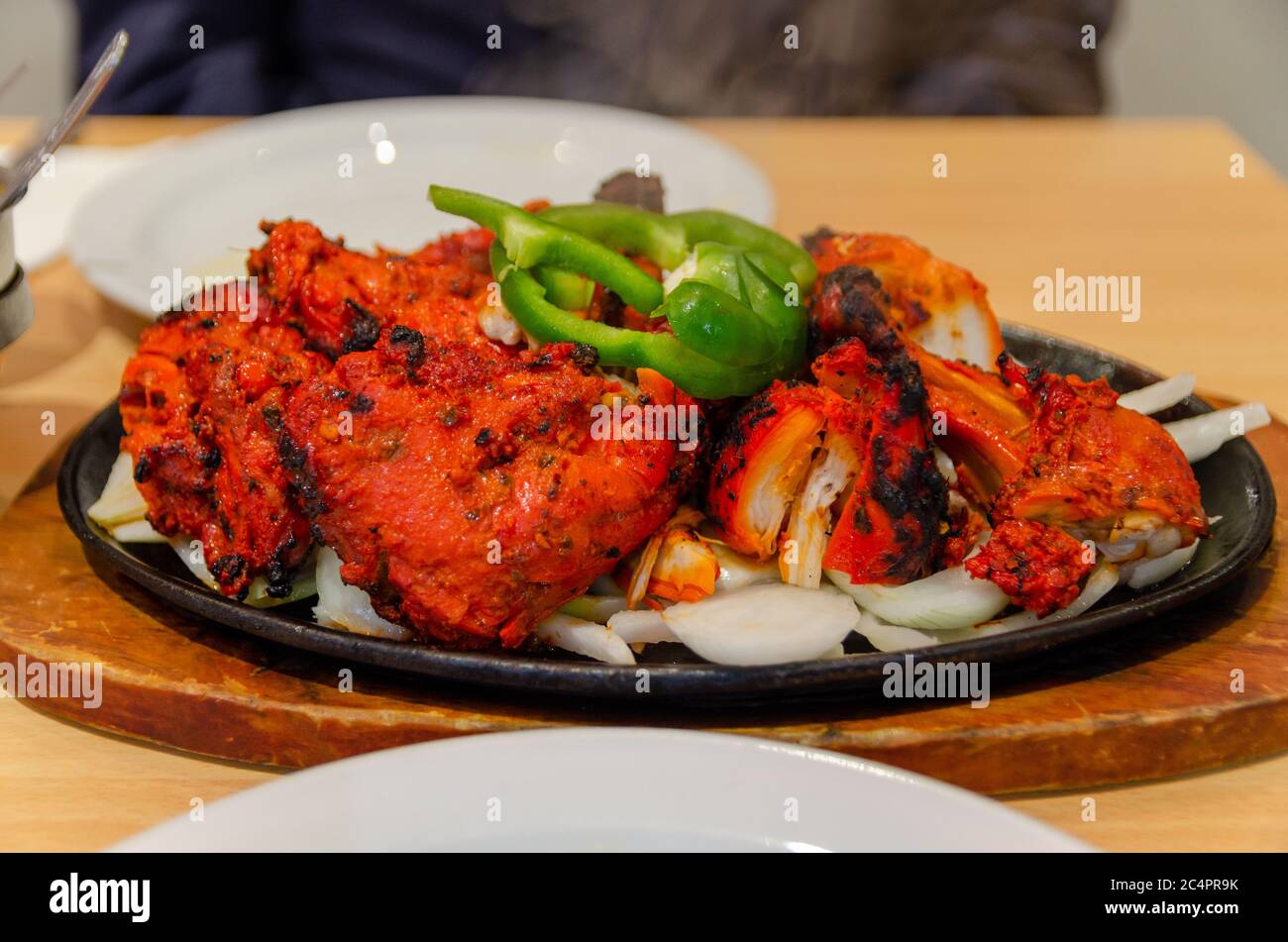 Tandoori Huhn auf einem Teller mit Zwiebel und grünem Paprika Stockfoto