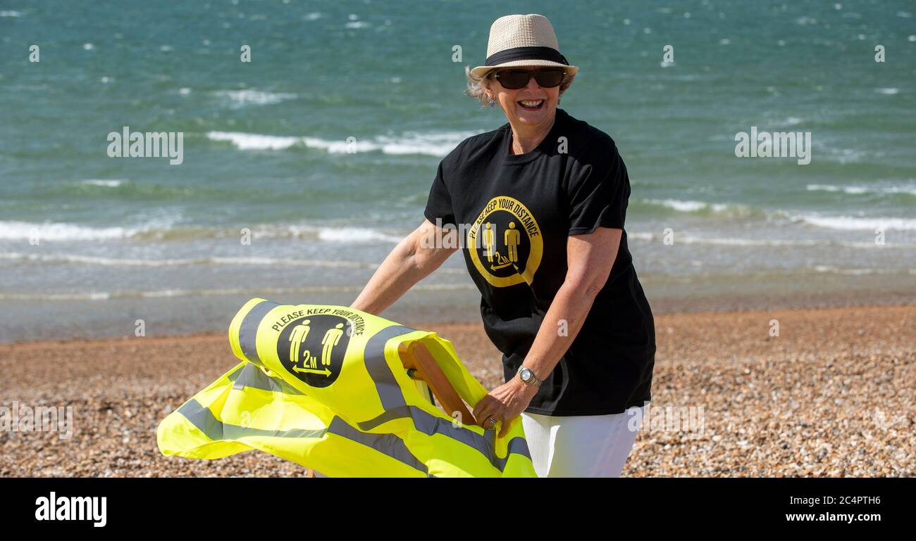 Southsea, Hampshire, England, Großbritannien. Juni 2020. Frau trägt soziale distanzierende T-Shirt und halten Sie Ihre Distanz his vis Weste an einem windigen Tag am Strand ein Stockfoto