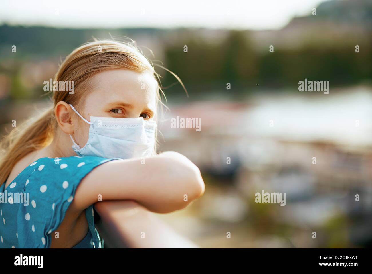 Leben während covid-19 Pandemie. Modernes Mädchen in blau insgesamt mit medizinischen Maske im Freien auf der Straße der Stadt. Stockfoto