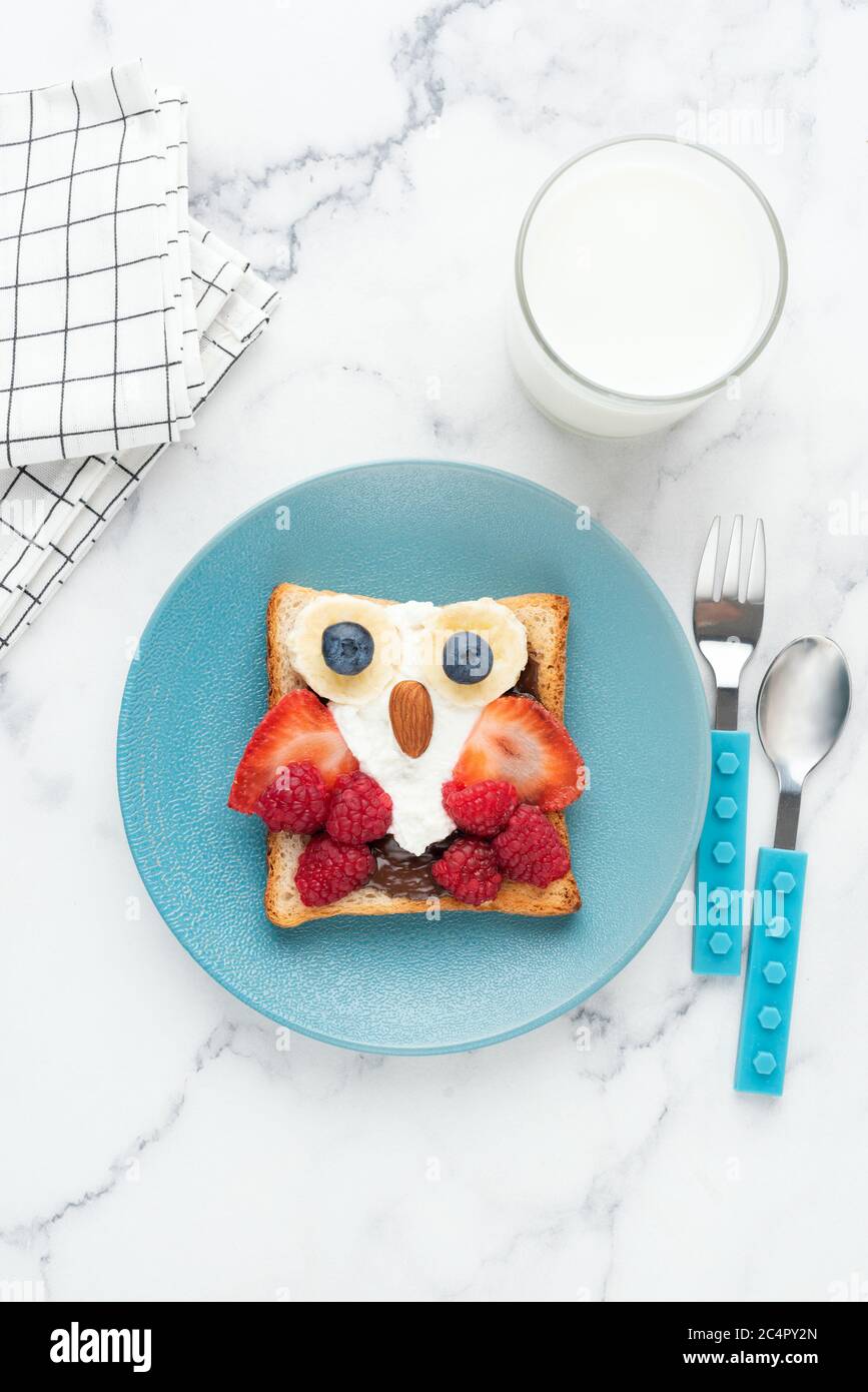 Frühstück Toast für Kinder geformt wie niedliche lustige Eule. Kinderfrühstück Essen auf blauem Teller, Draufsicht, vertikale Ausrichtung Stockfoto