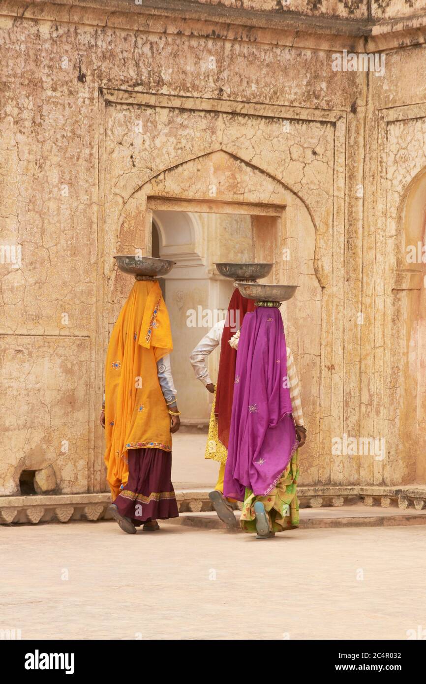 Weibliche Arbeiter Transport von Wasser und Gips in Schalen auf dem Kopf während der Restaurierung eines Palastes in Amber Fort in Jaipur, Indien. Stockfoto