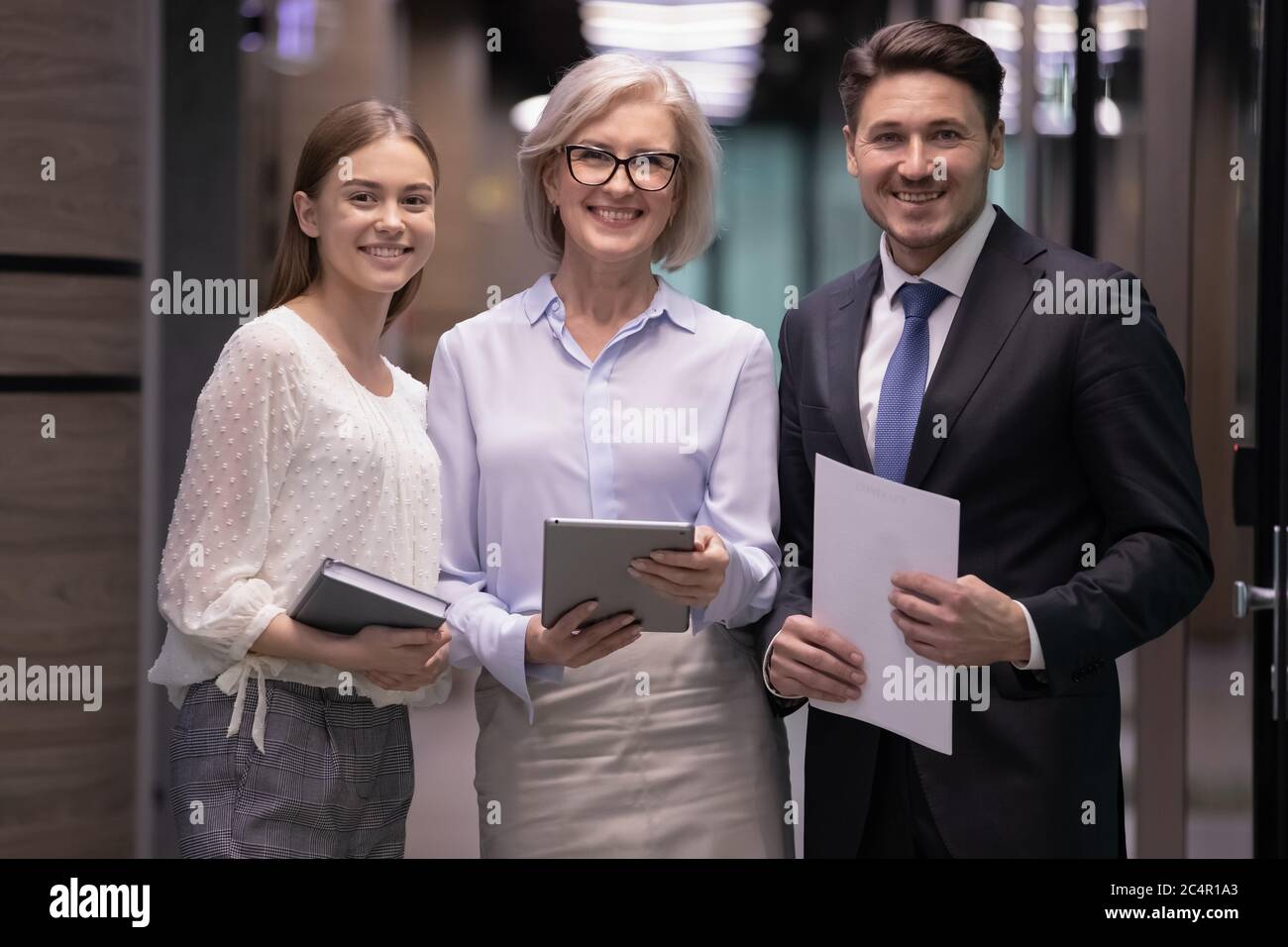 Lächelnde, selbstbewusste Geschäftsleute stehen im Büro zusammen Stockfoto