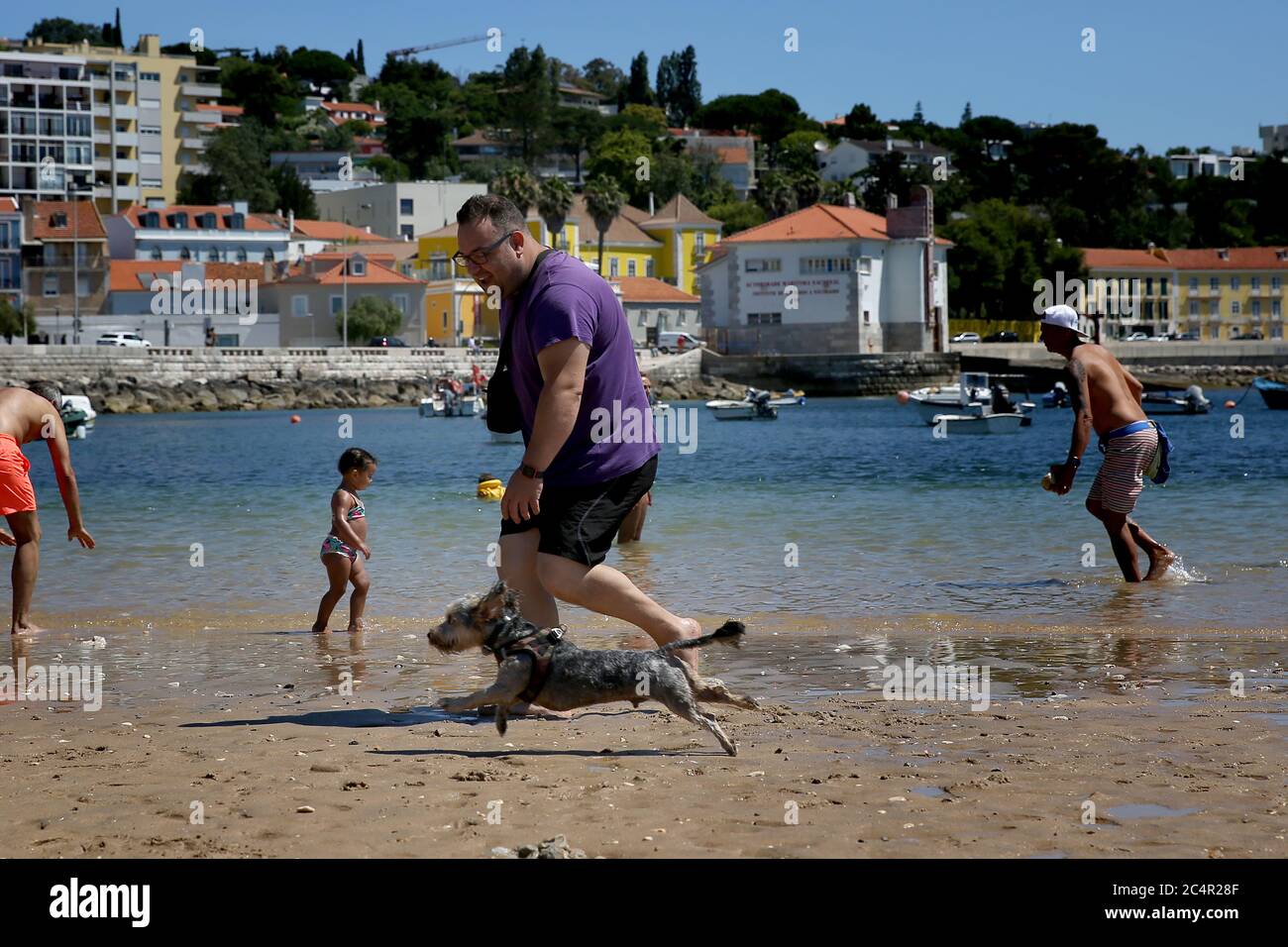 Oeiras, Portugal. Juni 2020. Ein Mann läuft mit seinem Hund am 28. Juni 2020 an einem haustierfreundlichen Strand in Oeiras, Portugal. Portugal wird seine COVID-19-Reaktion auf einen "Alarmzustand", den niedrigsten von drei Notständen, am 1. Juli weiter herabstufen, sagte der portugiesische Premierminister Antonio Costa am Donnerstag. Quelle: Pedro Fiuza/Xinhua/Alamy Live News Stockfoto