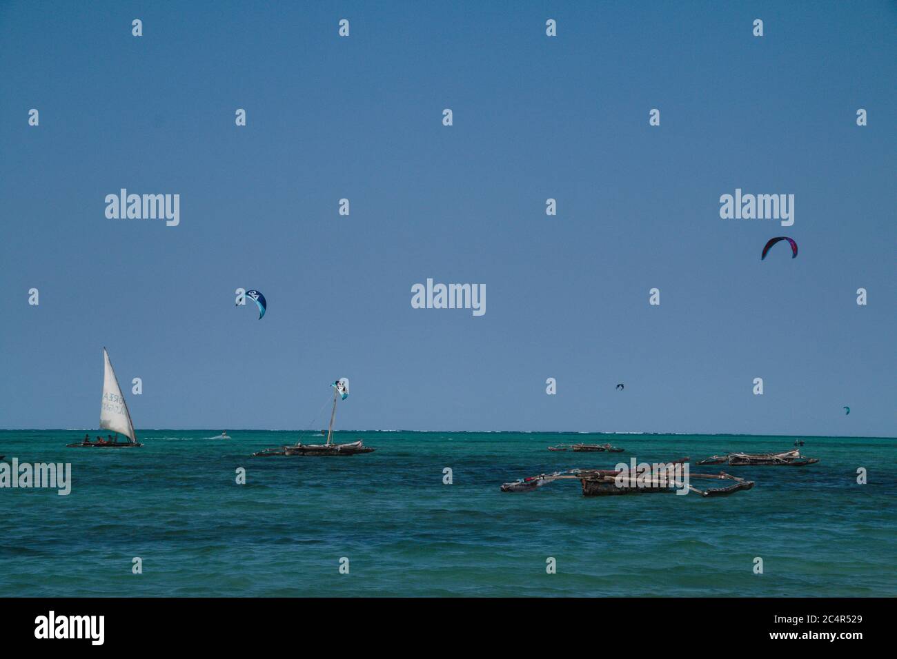 Eine Menge Kitesurfer und traditionelle Dhows im Wasser vor der Küste von Jambiani in Sansibar, Tansania Stockfoto