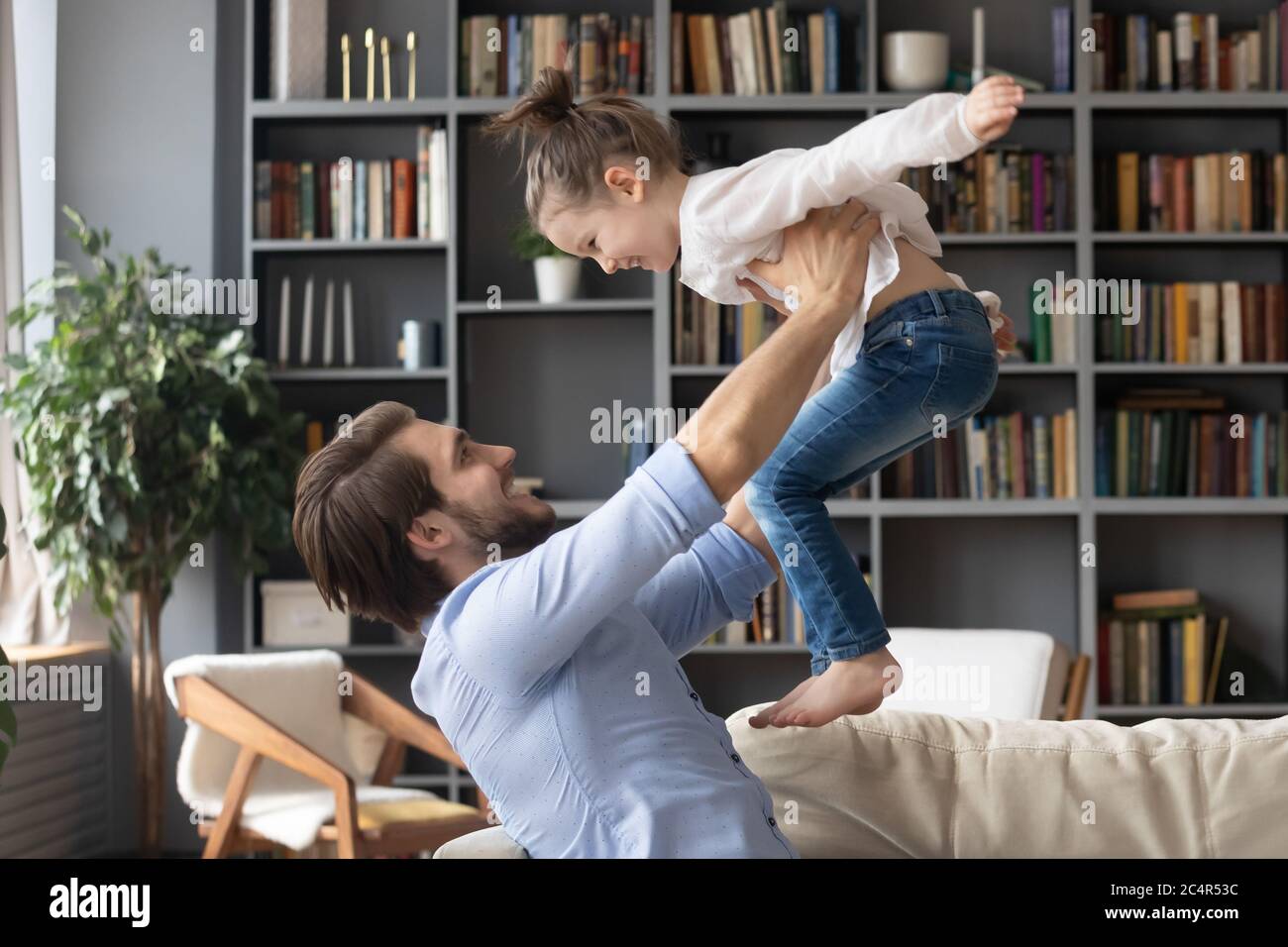 Glücklicher junger Vater hält kleine Tochter vorgeblich fliegen Stockfoto