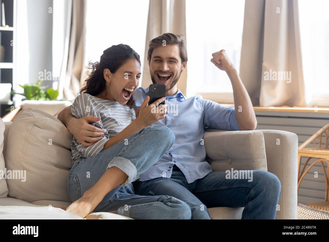 Überglücklich überrascht junge Paar Blick auf Telefonbildschirm Stockfoto