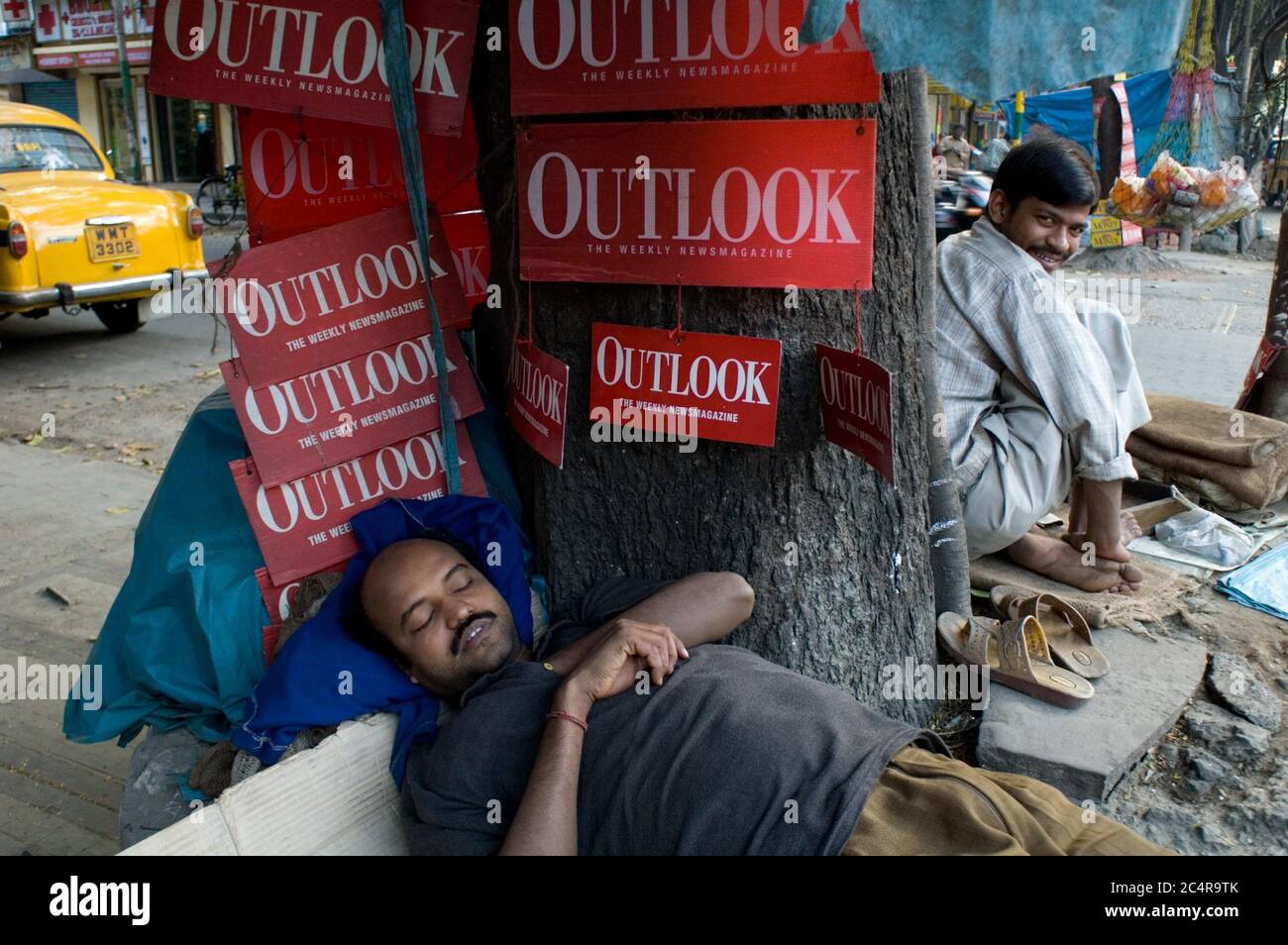 Ein Nickerchen im Triangulan Park unter Werbung für "Outlook", ein Magazin für aktuelle Angelegenheiten in Indien. Stockfoto