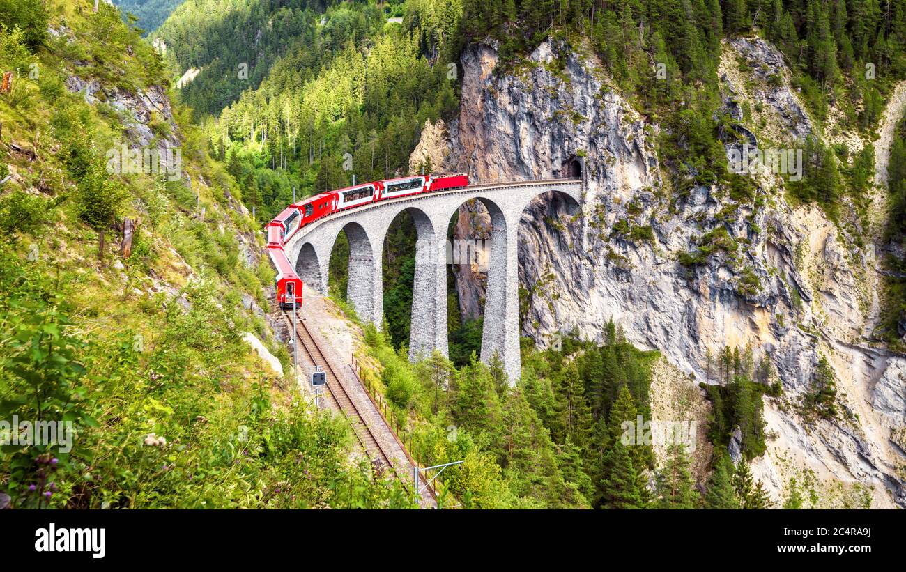 Landwasser Viadukt in Filisur, Schweiz. Es ist Wahrzeichen der Schweizer Alpen. Roter Zug von Bernina Express auf hoher Brücke in den Bergen. Panoramablick auf Stockfoto