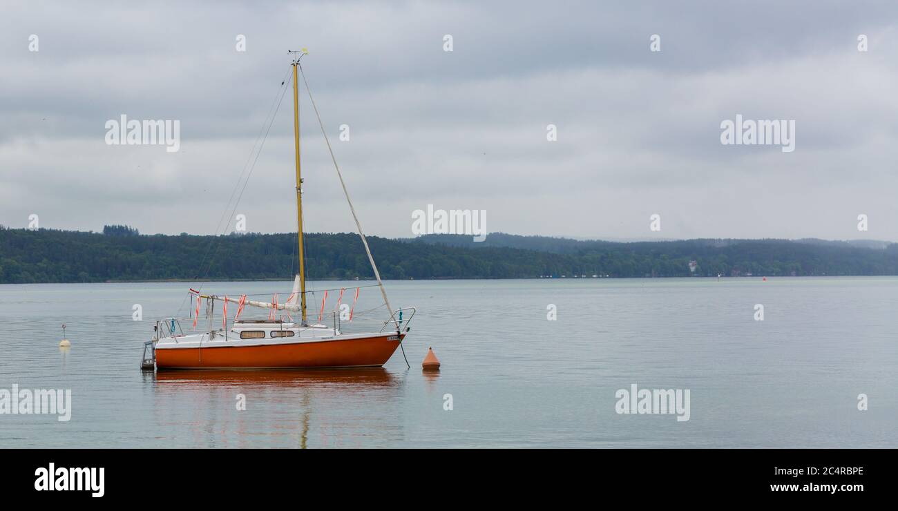 Rot gefärbtes Segelboot am Starnberger See. Symbol für Segeln. Stockfoto
