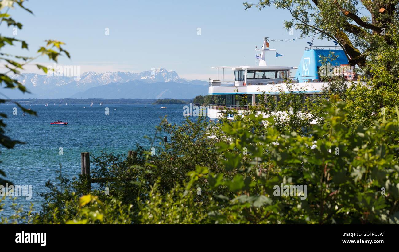 Kreuzfahrtschiff auf dem Starnberger See, eingerahmt von Ästen. Alpen im Hintergrund. Stockfoto