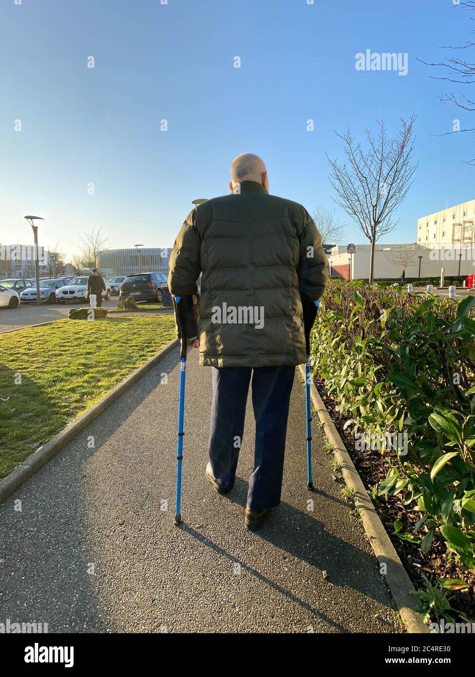 Straßburg, Frankreich - 20. Januar 2020: Rückansicht eines älteren Mannes, der mit Stöcken auf einem großen französischen Parkplatz im Krankenhaus unterwegs ist Stockfoto