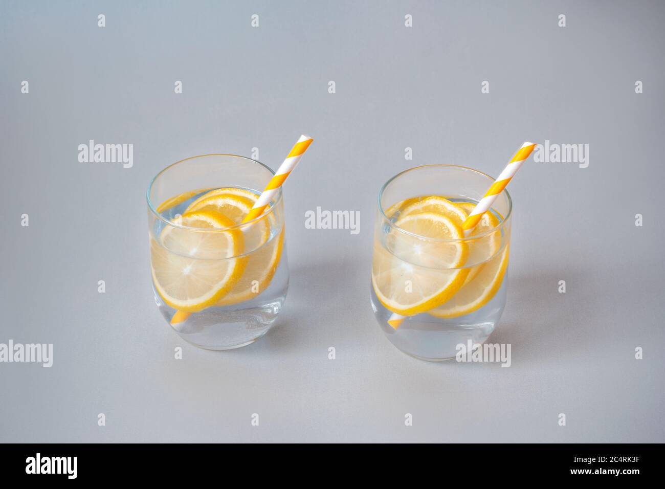 Zwei Gläser mit Limonade mit gelben Strohhalmen, lilafarbiger Hintergrund, Nahaufnahme. Stockfoto