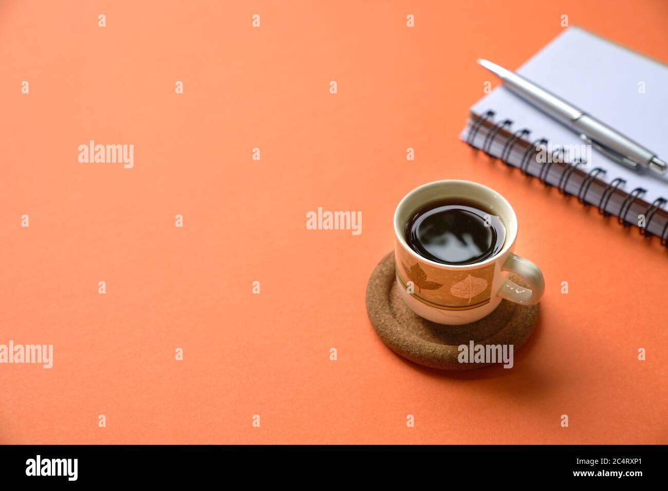 Kaffeetasse mit Notizblock auf der orangefarbenen Tischplatte. Speicherplatz kopieren. Stockfoto