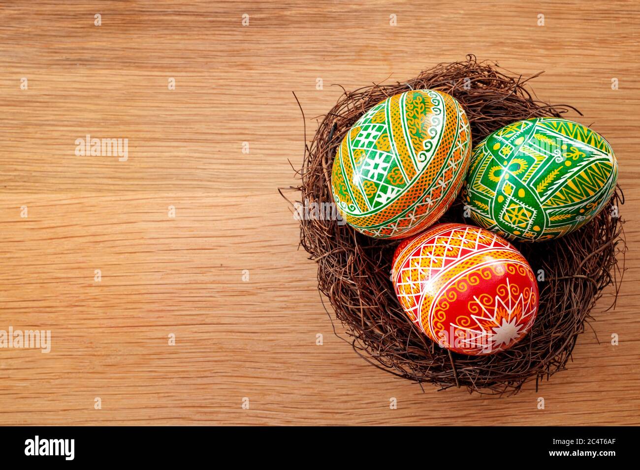 Osterferien und Frühlingsfest Konzept mit drei ostereiern mit einem komplexen Muster in einem Vogelnest isoliert auf einem Holzhintergrund wi dekoriert Stockfoto