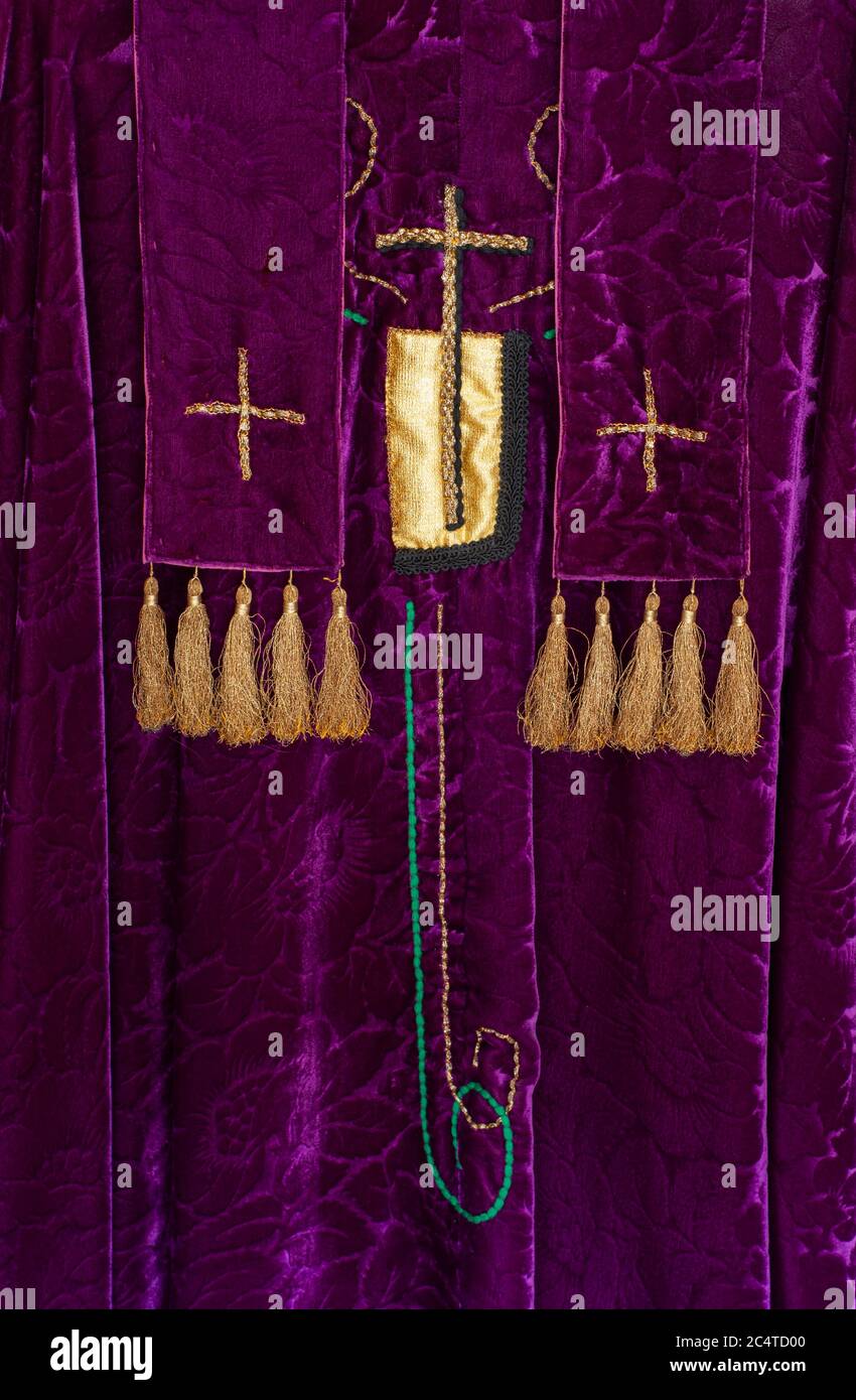 Liturgische Gewänder des Priesters. Violetter Samt mit goldenen Kreuzen und Quasten. Nahaufnahme zeigt Symbole des christlichen Gottesdienstes an Festtagen. Stockfoto