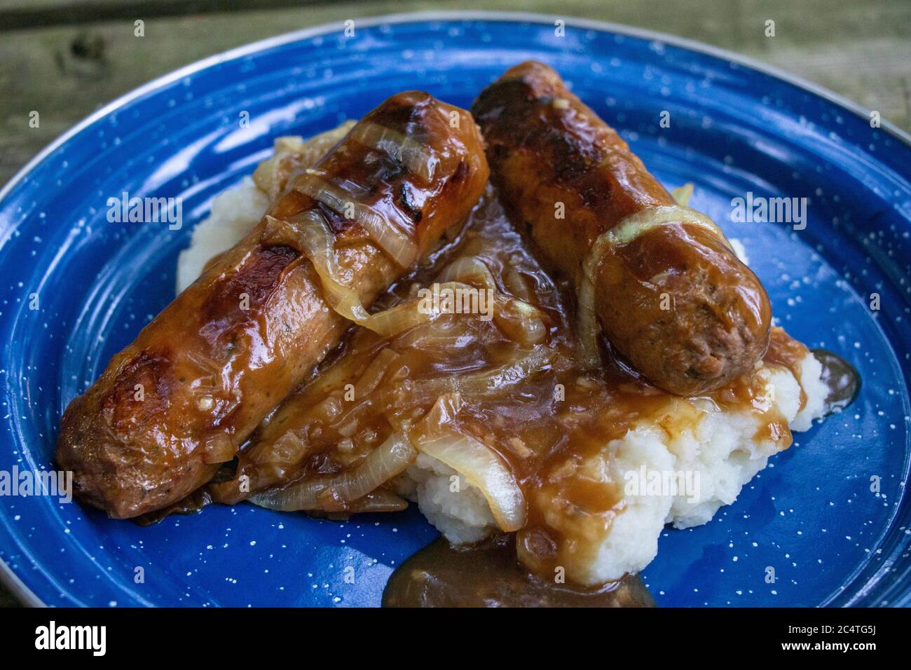 Vegane Bangers & Mash mit Fleischwürsten (fleischfrei, fleischlos), Soße, Kartoffelpüree in einer Camping-Emaille-Platte Stockfoto