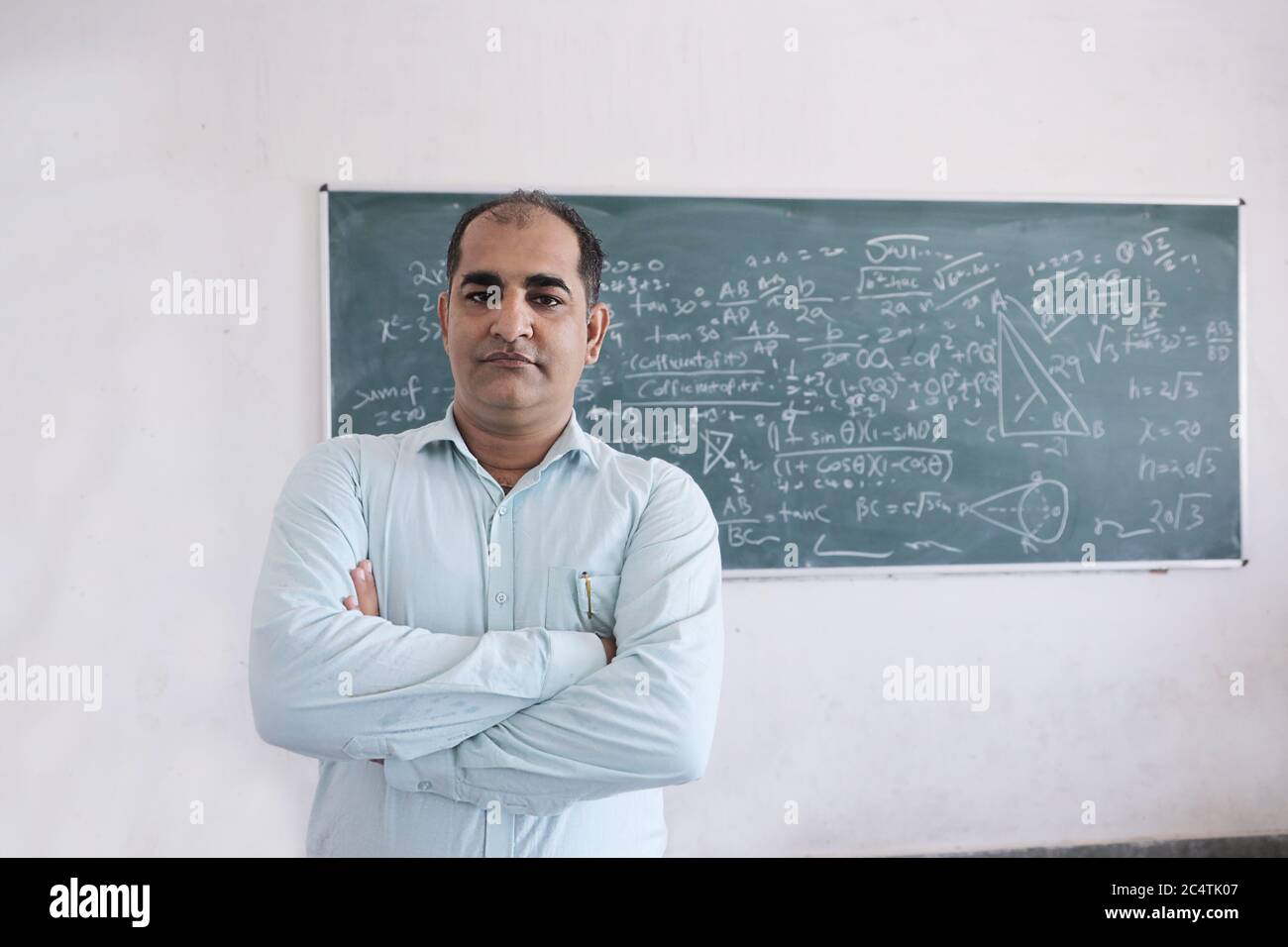 Männliche Lehrer stehen gegen Tafel Unterricht Mathematik in Klassenzimmer, Schule und Bildungskonzept. Stockfoto