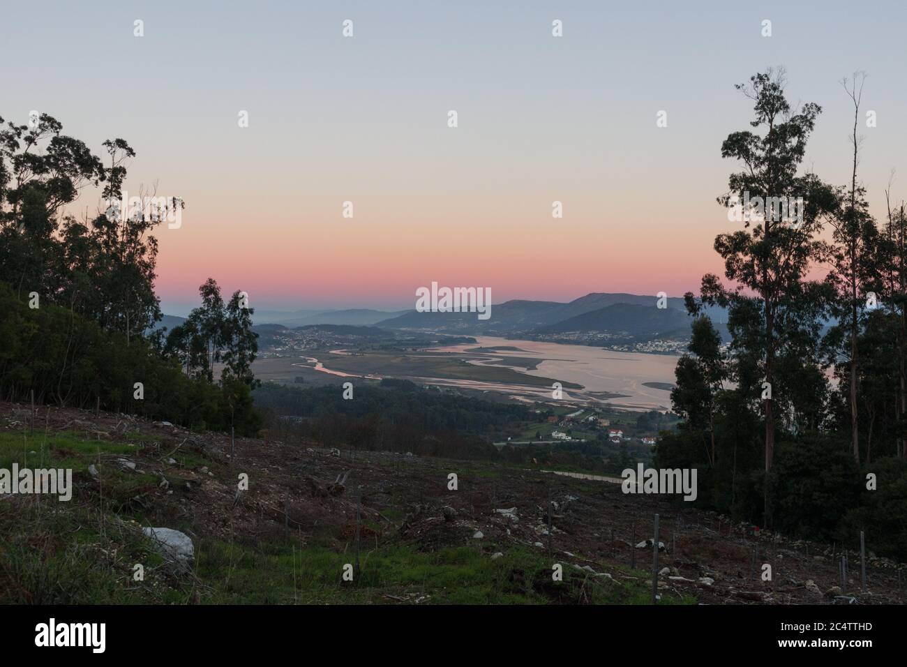 Langer Fluss, umgeben von hohen Bergen, die unter dem Blau schimmern Und rosa Himmel Stockfoto