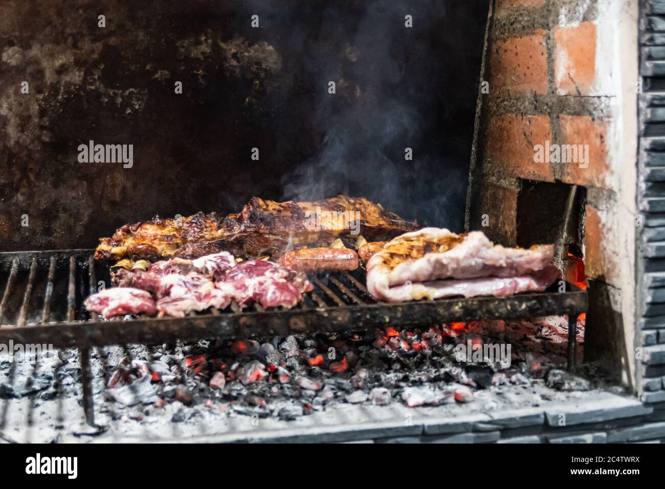 'Parrillada' Argentinischer Grill auf Live-Kohle (keine Flamme), Rindfleisch 'Asado', Brot, 'Chorizo' und gegrillte Rippchen mit einem heißen Rack, Nahaufnahme, Fokus se Stockfoto