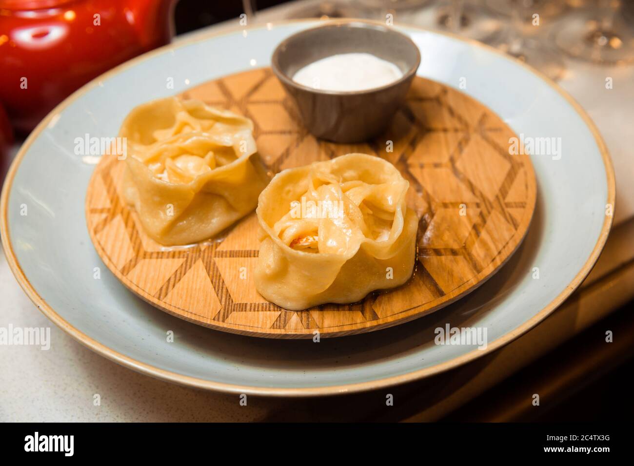 Saftige Manti auf einem weißen Teller. Serviert mit Sauce. Traditionelles Gericht. Stockfoto