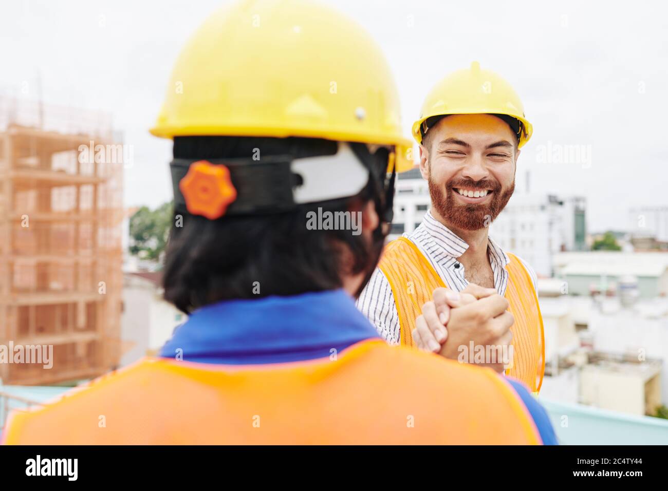 Glückliches Lächeln Oberingenieur schüttelt Hand der Auftragnehmer bei der Besprechung auf der Baustelle am Morgen Stockfoto