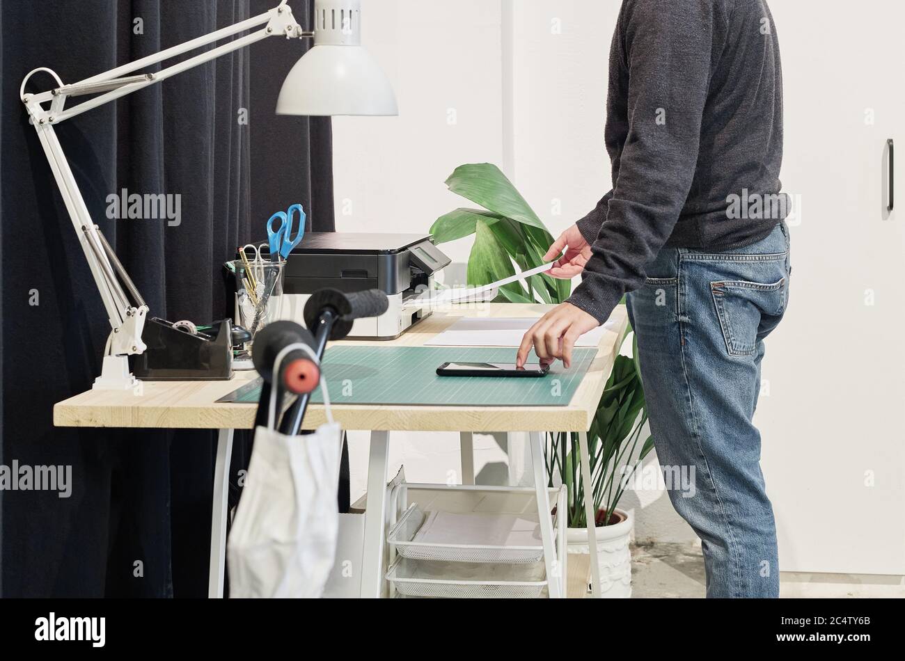 Männlicher Mitarbeiter, der Dokumente auf dem Schreibtisch druckt Stockfoto