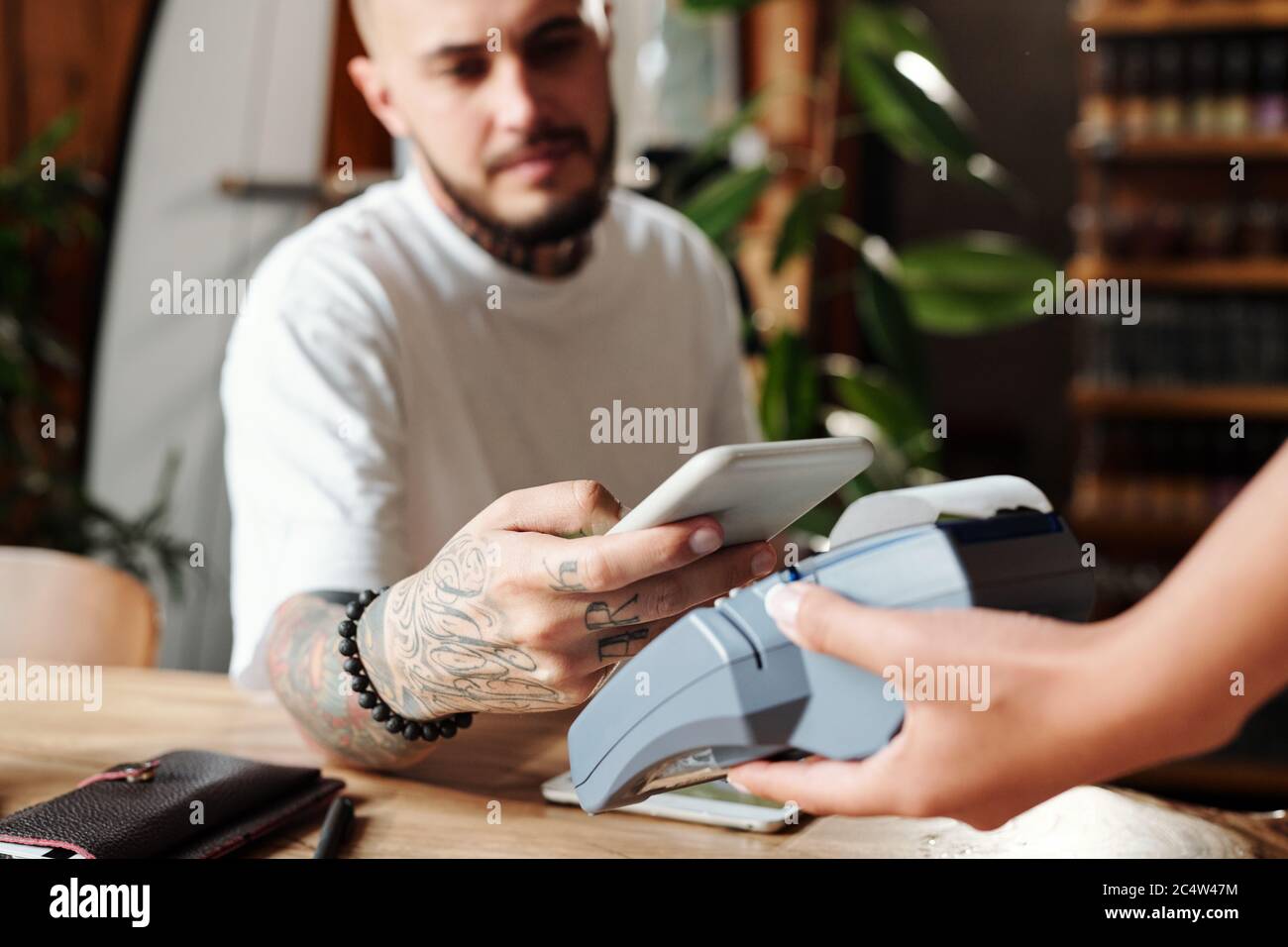 Nahaufnahme des Mannes mit Tattoos Bezahlung mit Smartphone nach dem Abendessen in einem modernen Café Stockfoto