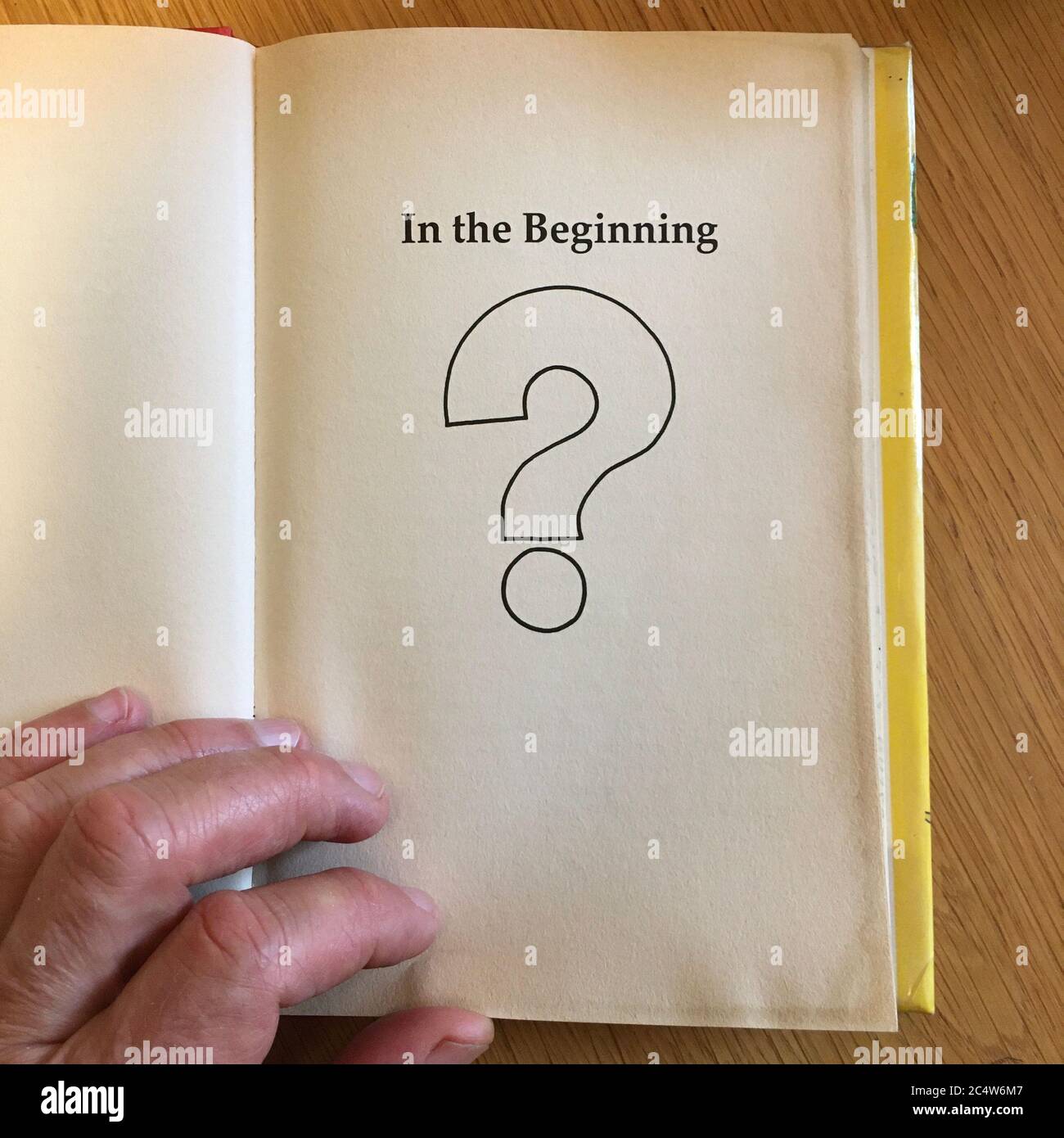 Eine Hand, die die Seite eines Buches mit der Überschrift „am Anfang“ dreht Stockfoto