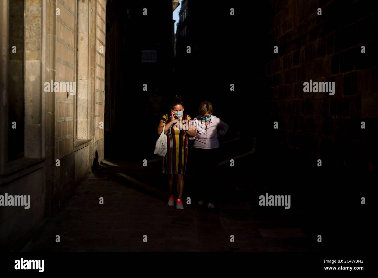 Frauen mit Gesichtsmasken gehen durch Barcelonas Straßen im Gotischen Viertel. Die spanische Regierung genehmigte die Regeln der "neuen Normalität" mit einem Dekret, in dem Sicherheitsmaßnahmen für ein Leben nach der Sperrung aufgeführt sind. Stockfoto