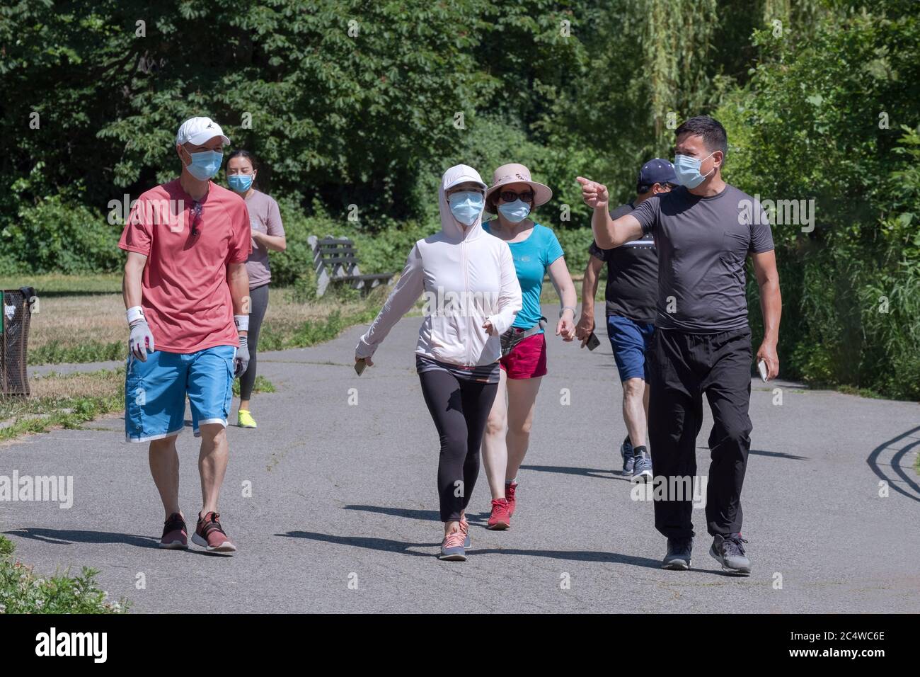 Eine Gruppe von asiatischen amerikanischen Männern und Frauen üben Wandern mit chirurgischen Masken. Im Kissena Park in Flushing, Queens, New York City Stockfoto