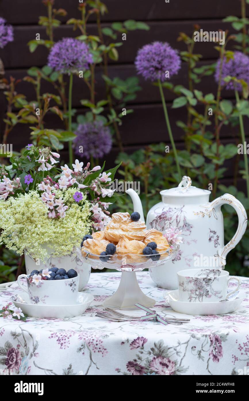 Tischdekoration mit Cremepuffs und Vintage Porzellan im Frühlingsgarten Stockfoto