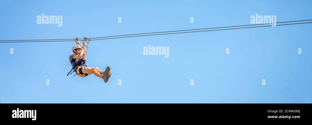 Teenager Spaß auf einer Zipline auf Panorama-blauen Himmel Hintergrund mit Kopierraum. Stockfoto