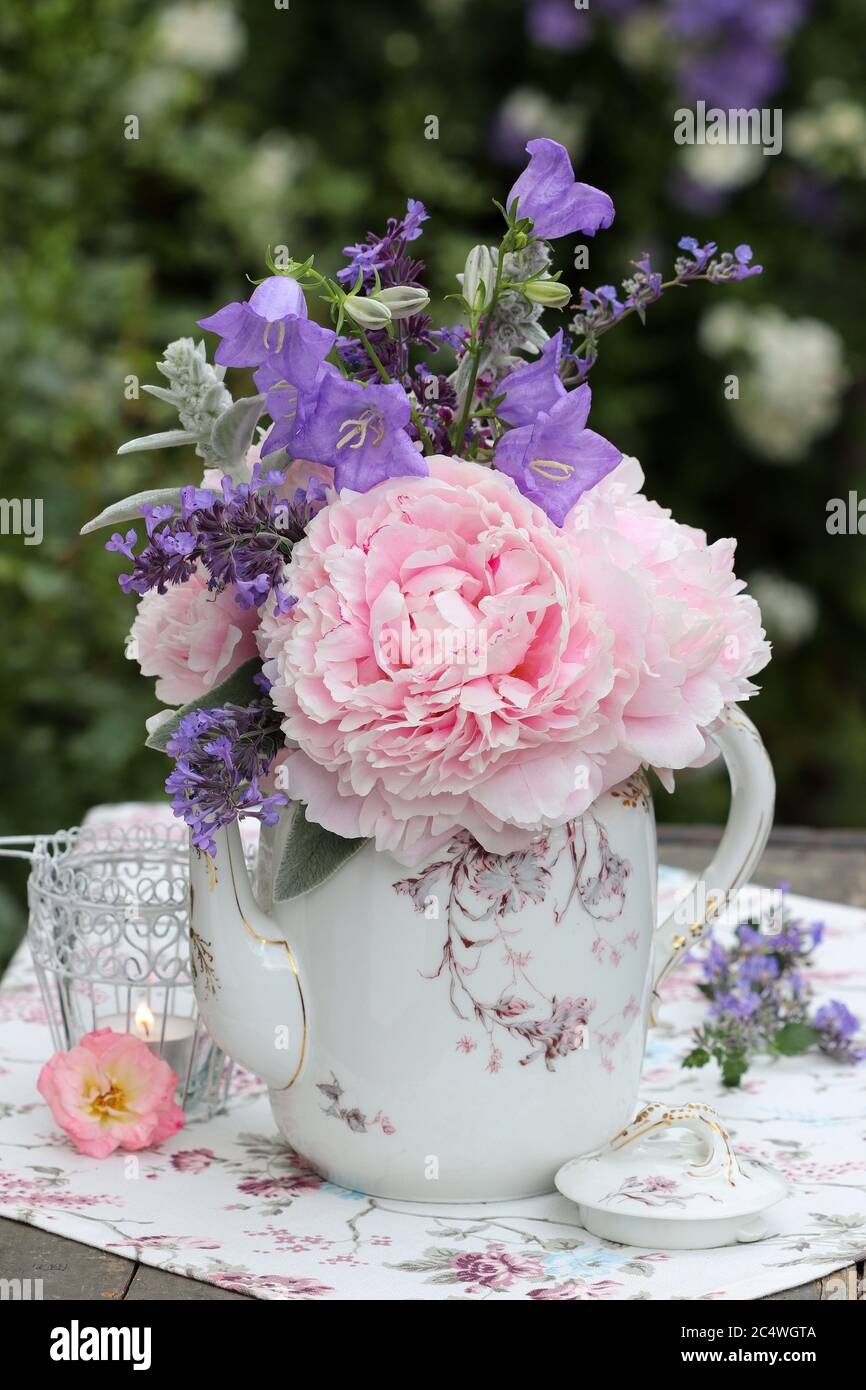 Romantische Dekoration mit Blumenstrauß in Vintage-Kaffeekanne Stockfoto