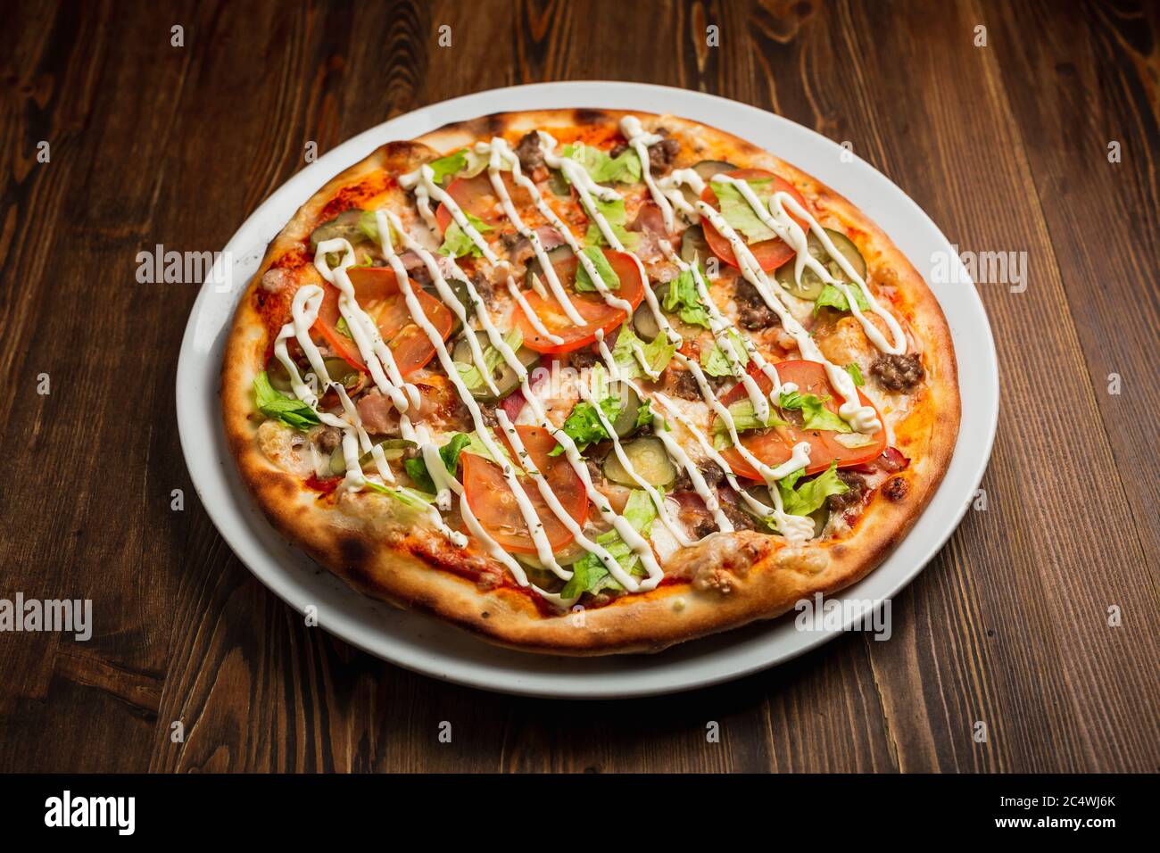 Speck, Fleisch, Gurken, Tomaten, Salat Pizza mit Mayonnaise, Holzhintergrund, Low-Key Stockfoto