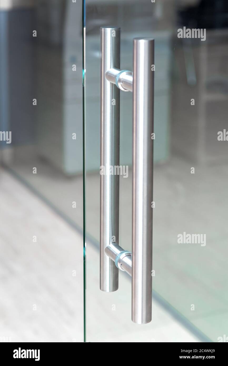 Der Metallgriff der Glastür im Innenraum des Raumes, Nahaufnahme. Stockfoto