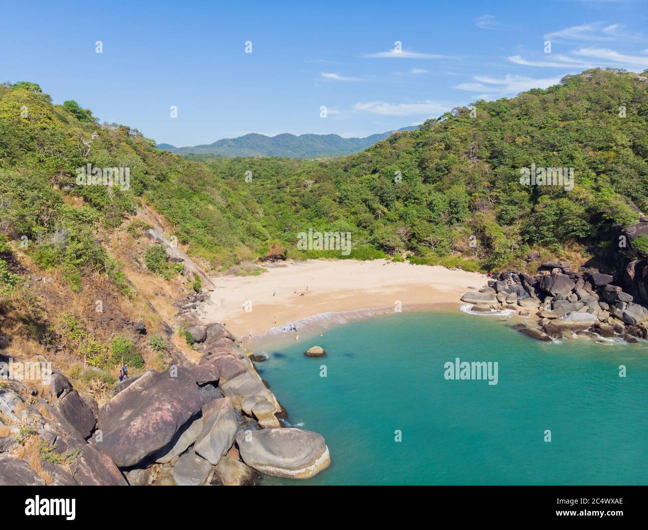 Schöner geheimer Strand Butterfly in Goa, Indien. Luftaufnahme des unberührten Strandes mit felsigen Bucht und Wellen, die zusammenbrechen. Stockfoto